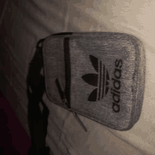 a grey adidas purse with a black strap