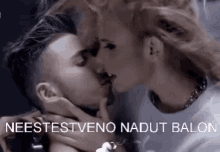 a man and a woman are kissing in front of a sign that says neestestvono nadut balon .