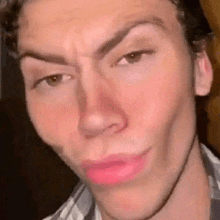 a close up of a man 's face with pink lipstick on his lips making a funny face .