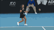 a woman holding a tennis racquet on a tennis court with a sign that says 100 years in the background