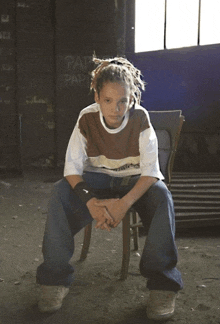 a young boy with dreadlocks sits in a chair in front of a wall that says pap pap