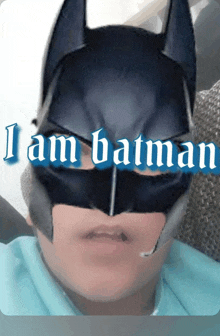 a person wearing a batman mask with the words " i am batman " above them