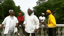 a group of men are standing on a railing and one of them is wearing a yellow shirt with the word rosie on it