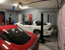 two cars are parked in a garage with a sign on the wall that says camaro