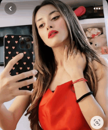 a woman in a red dress takes a selfie with her phone