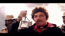 a man with a mustache is holding a bag in his hands .