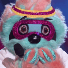 a stuffed animal is wearing a pink and yellow headband and goggles