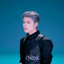 a young man wearing a black jacket with choom studio written on it
