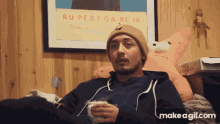 a man is sitting in front of a poster that says rupert garcia