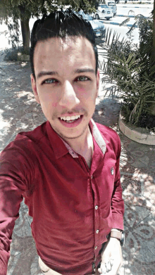 a young man wearing a red shirt takes a selfie