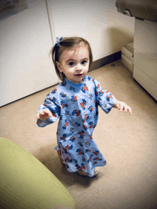 a little girl wearing a blue hospital gown with a mickey mouse print