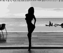 a black and white photo of a woman standing in front of a pool