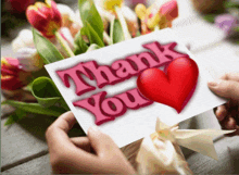 a person is holding a thank you card in front of flowers