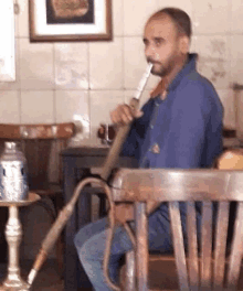 a man is sitting in a chair and smoking a hookah .