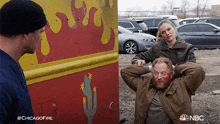 a man with blood on his face is being held by a woman in front of a yellow and red truck with a cactus painted on it