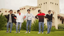 a group of young men are standing in front of a building holding hands