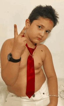 a shirtless boy wearing a red tie and a watch makes a peace sign