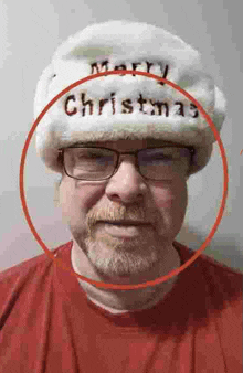 a man with glasses and a beard is wearing a santa hat and a red shirt .