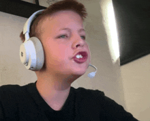 a young boy wearing headphones and a microphone making a face