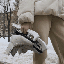 a person is holding a pair of ice skates with the letters sns on them