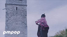 a person standing in front of a stone tower with the words pmpop written on the bottom