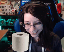 a woman wearing glasses and headphones holds a roll of toilet paper