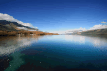 a lake with mountains in the background and a blue sky with clouds