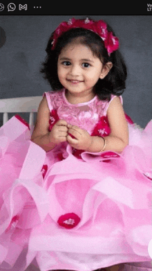 a little girl wearing a pink dress with ruffles