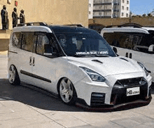 a white van that looks like a nissan gtr is parked on a sidewalk .