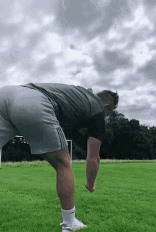 a man is bending over on a soccer field .