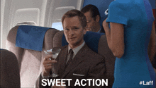 a man in a suit is holding a martini on an airplane and the words sweet action are above him