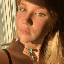 a close up of a woman 's face with a turquoise necklace