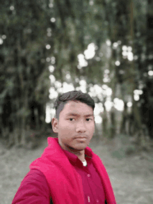 a young man wearing a red shirt and a red jacket is taking a selfie