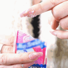 a close up of a person 's hand holding a pink and blue item with the word fun on it