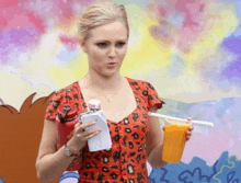 a woman is holding a cup of orange juice and a bottle of water