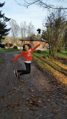 a girl jumping in the air wearing a red shirt that says ' i am a girl ' on it