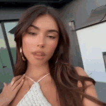 a close up of a woman wearing a white halter top and earrings .