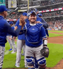 a group of baseball players are standing on a field and one of them is wearing a blue uniform .