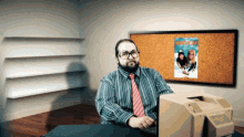 a man sits at a desk in front of a computer with a poster on the wall that says ' a christmas story '