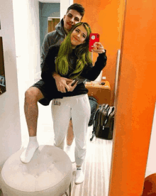 a woman with green hair is taking a selfie with her boyfriend