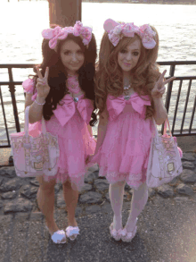 two girls in pink dresses are standing next to each other and giving peace signs