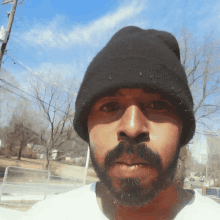 a man with a beard wearing a black beanie looks at the camera