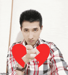 a man in a plaid shirt is holding a broken heart in his hand