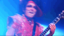 a man in a clown costume is playing a guitar on a stage