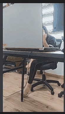 a woman is sitting at a desk with her legs crossed and a laptop on it .