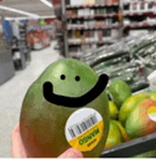 a person is holding a mango with a face drawn on it