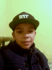 a young boy wearing a black hat with the letter mt on it