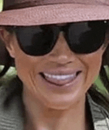 a close up of a woman wearing a hat and sunglasses .