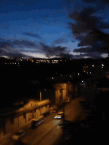 a blurry picture of a city at night with a blue sky and clouds