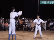 two karate fighters are standing in front of a crowd with a green sign behind them that says 저작권 으로 인해